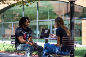 Two students sit in courtyard studying together