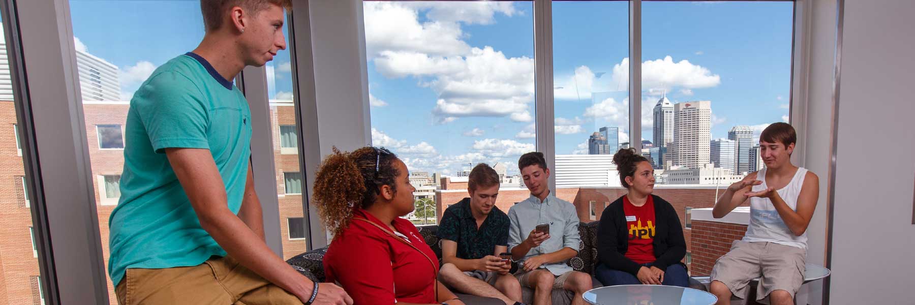 Students hang out in a room with downtown Indianapolis in the background. 