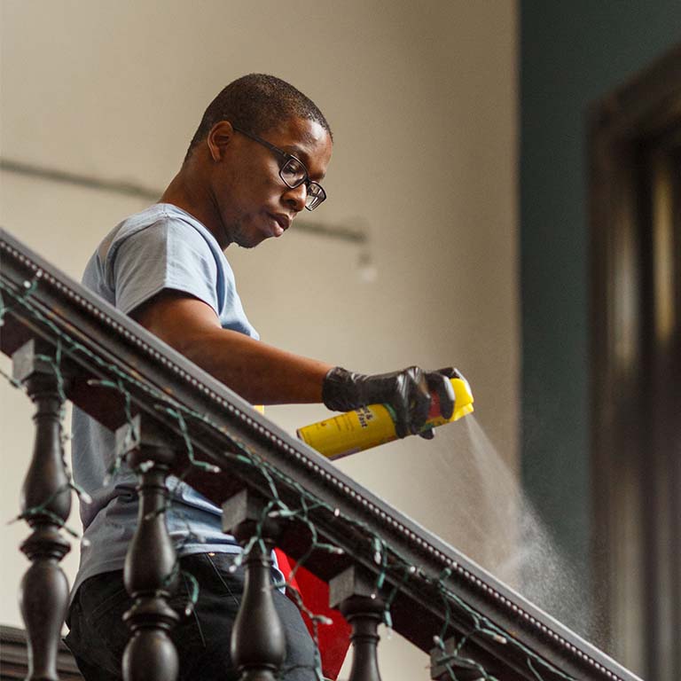 A male student cleans a banister.
