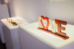 White museum display shelf with a small sign that says love in red and white letters.