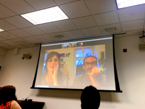 students looking at a class room projector screen that shows Olinka Vištica and Dražen Grubišić participating on a zoom call. 