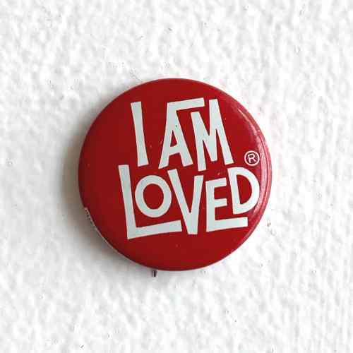 A round red pin with the words "I am loved" in white